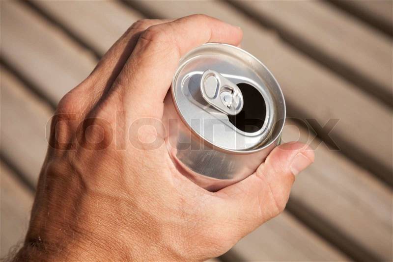 Aluminum can of beer in a male hand, summer outdoor photo, stock photo