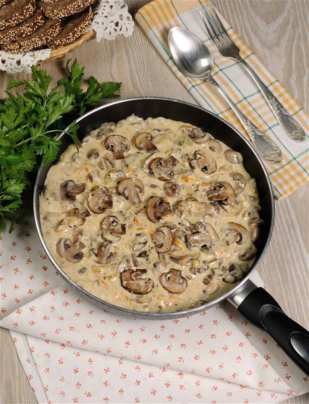 Fried mushrooms in a creamy sauce cooked in a frying pan, stock photo