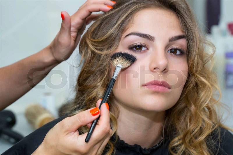 Makeup makes a girl in a beauty salon, stock photo