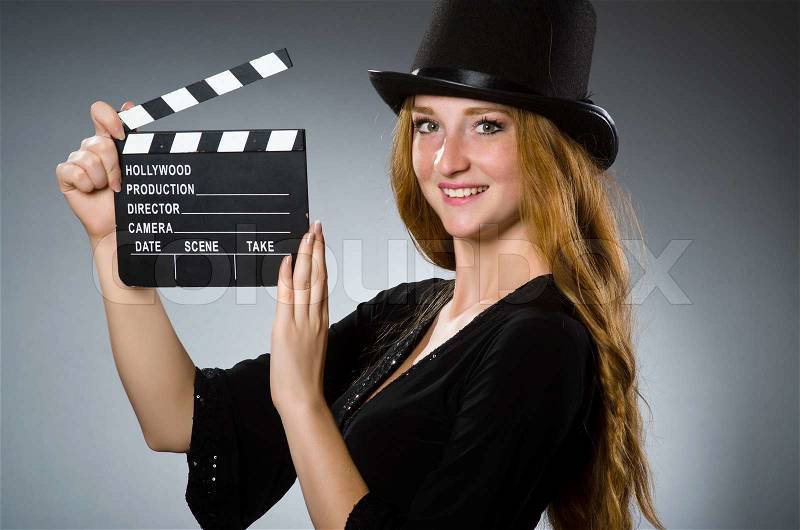 Woman with movie clapboard against grey background, stock photo