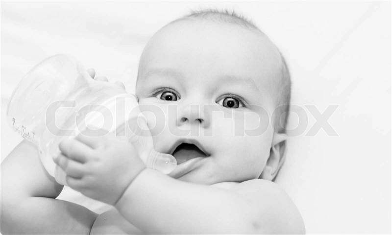 Happy baby is drinking water from a bottle ( black and white ), stock photo