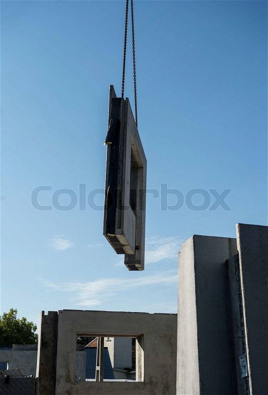 Crane lifting parts of prefabricated house in place, stock photo