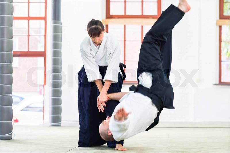 Man and woman fighting at Aikido training in martial arts school , stock photo