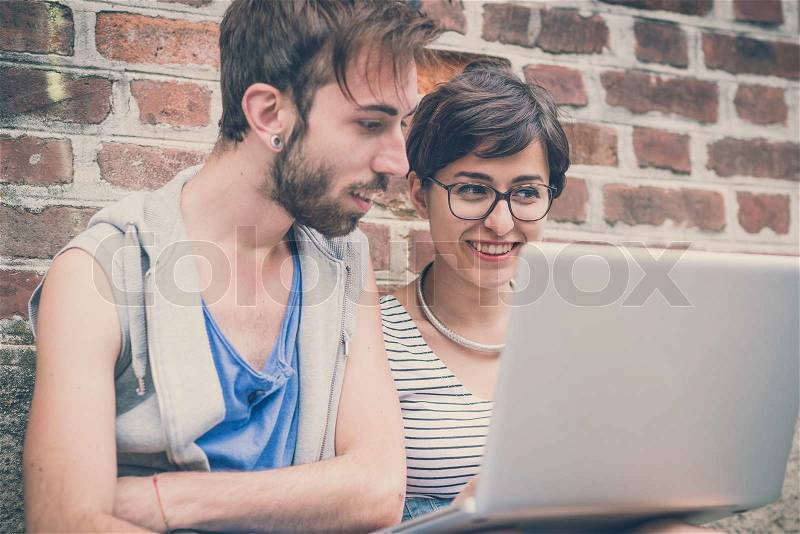 Couple of friends young man and woman using laptop in the city, stock photo