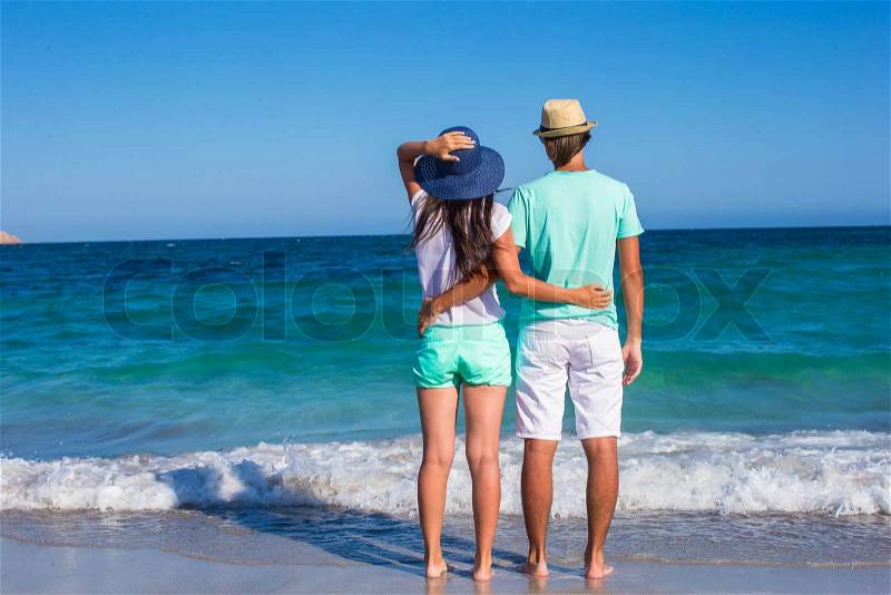 Back view of young couple walking at beach during tropical vacation in Sardinia, stock photo