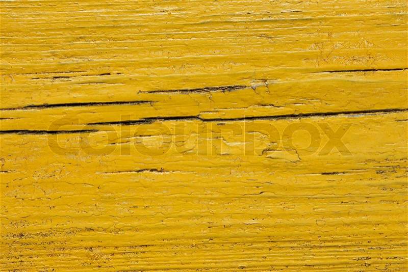 Detail the old cracked wooden board painted in yellow close-up, stock photo