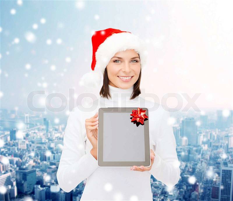 Christmas, technology, present and people concept - smiling woman in santa helper hat with blank screen tablet pc computer over snowy city background, stock photo