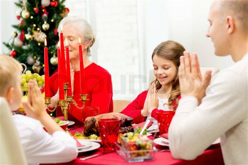Family, holidays, generation, christmas and people concept - smiling family having dinner and praying at home, stock photo