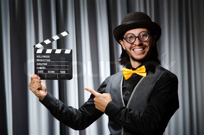Funny man with movie board against curtain, stock photo