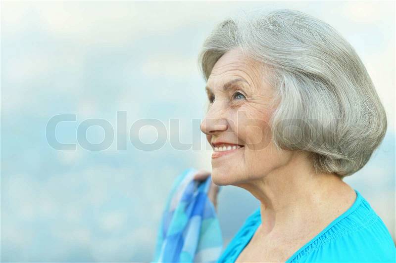 Nice smiling old woman on sky background, stock photo