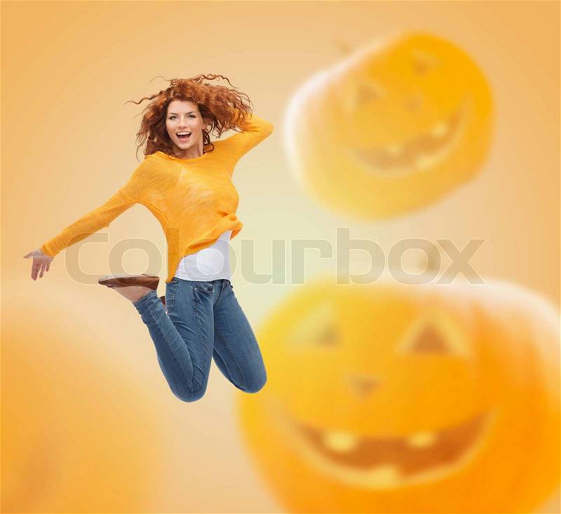 Happiness, freedom, holidays and people concept - smiling young woman jumping in air over halloween pumpkins background, stock photo