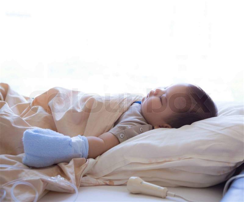 5 months old sick baby with viral infection, receiving infusion therapy while asleep in hospital bed, stock photo