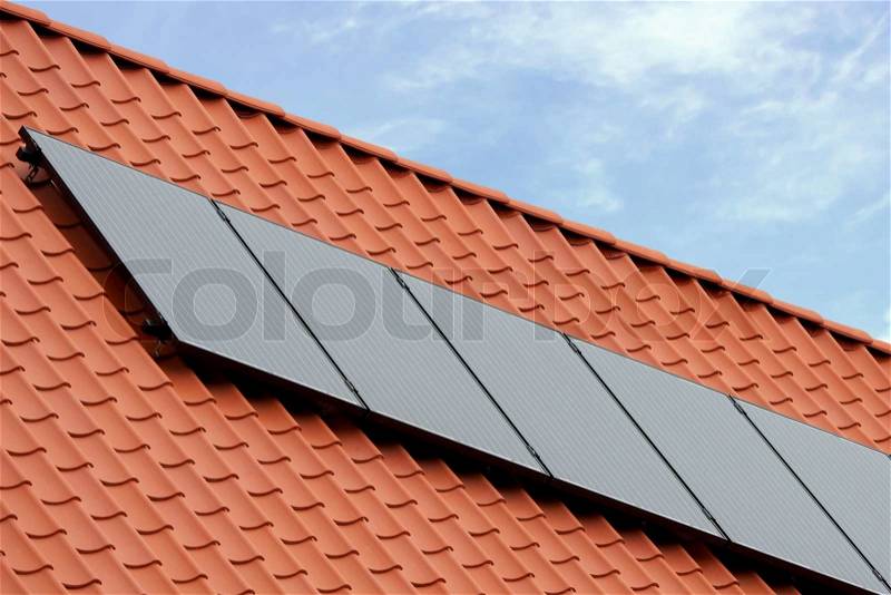 Flat plate solar thermal collectors on a red tile roof, stock photo