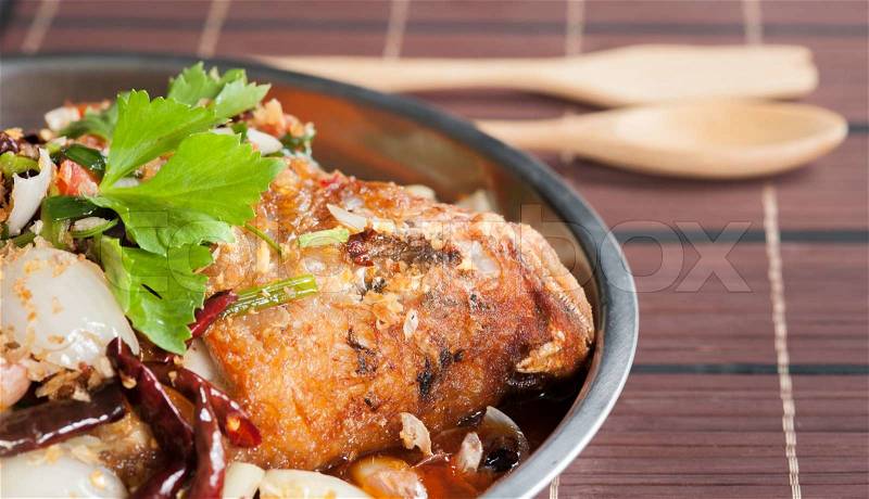 Fried fish with fresh herbs and sweet spicy sauce on wood and spoon,Thai style, stock photo