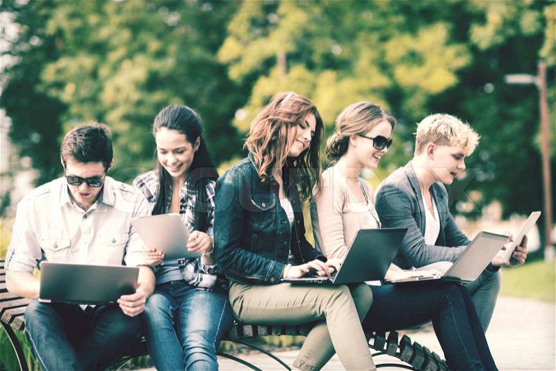 Summer, internet, education, campus and teenage concept - group of students or teenagers with laptop and tablet computers hanging out, stock photo