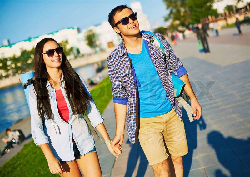 Amorous dates with backpacks sightseeing in a city, stock photo