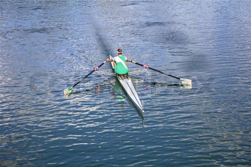 Women Rower in a boat, rowing on the tranquil lake, stock photo