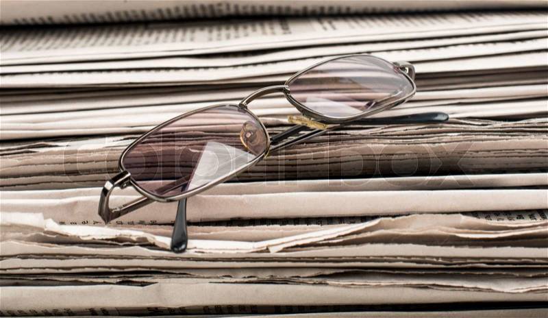 Newspaper with glasses closeup, stock photo