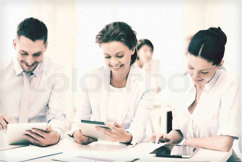 Smiling business team working with tablet pcs in office, stock photo