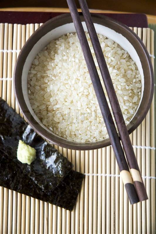Uncooked japanese rice in bowl with chopsticks, stock photo