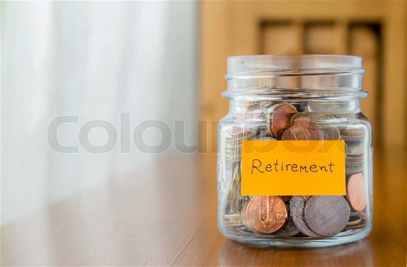 World coins in glass savings jar with retirement plan label, stock photo