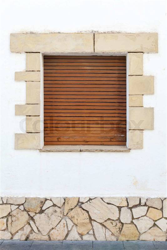 Old white stone wall with brown wooden shutters in the window. Background texture, stock photo