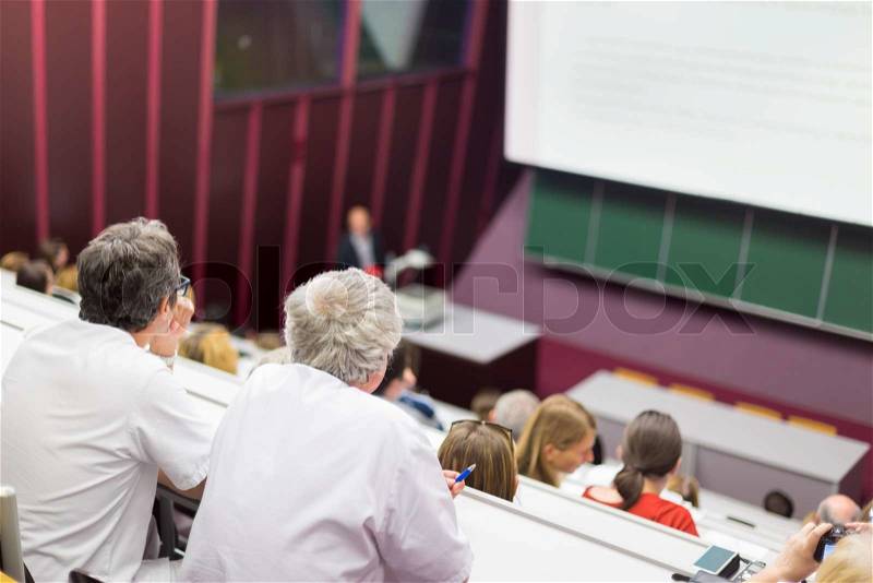 Lecturer at university. Healthcare expert giving a talk to medical faculty professors. Participants listening to lecture and making notes, stock photo