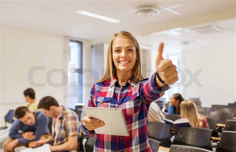 Education, high school, teamwork and people concept - group of smiling students with tablet pc computer howing thumbs up in lecture hall, stock photo