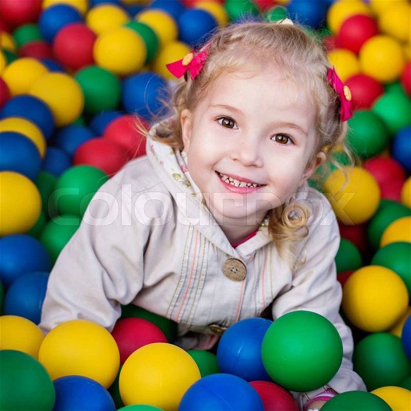 Happy little girl playing on colorful balls playground , stock photo