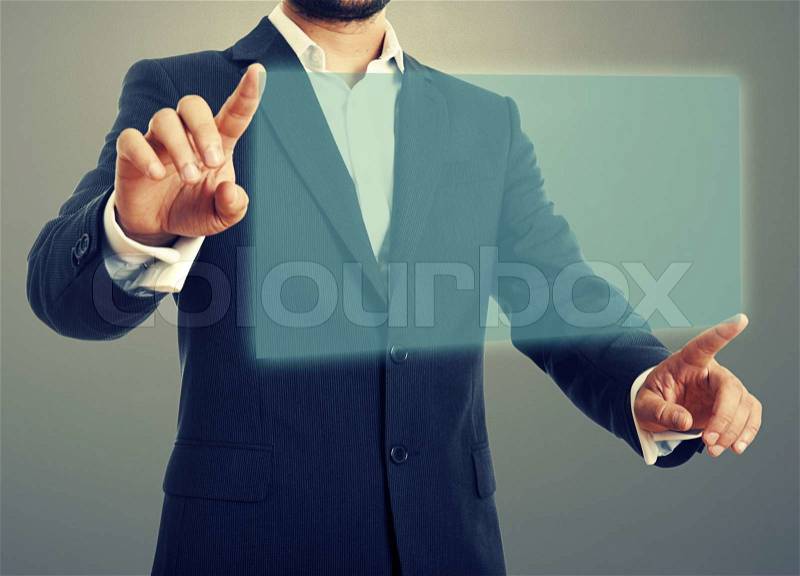 Businessman opening virtual screen over dark background, stock photo