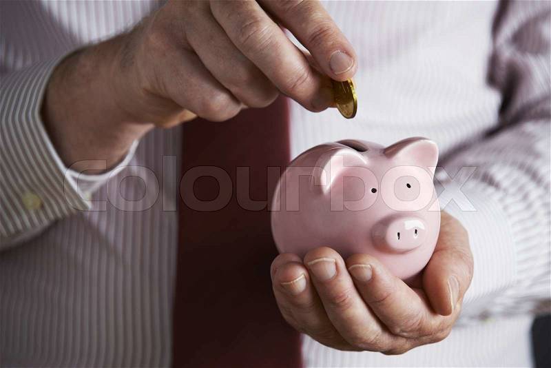 Businessman Putting Coin Into Piggy Bank, stock photo