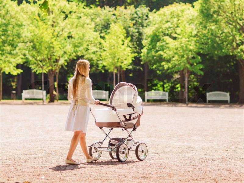 Family, child and parenthood concept - happy mother walking with baby stroller in park from back, stock photo