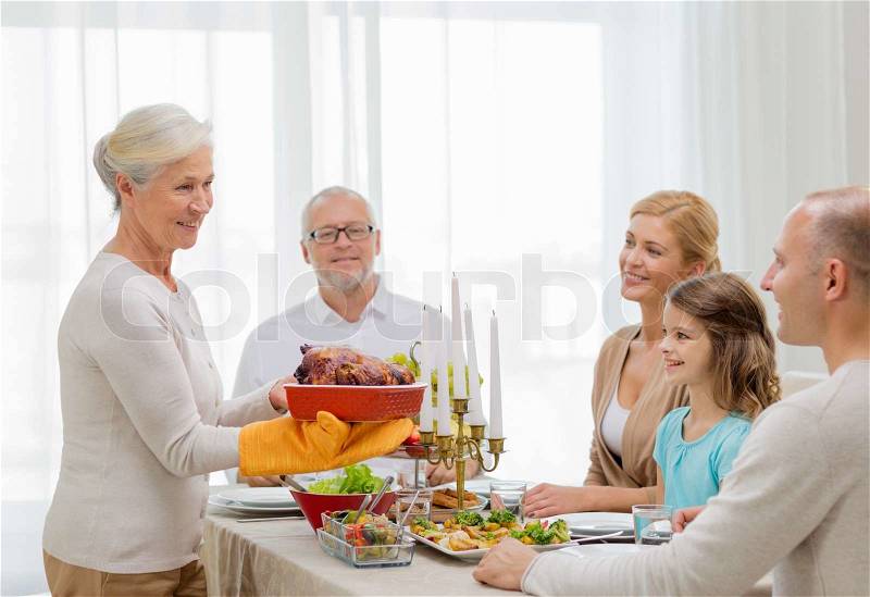 Family, holidays, generation and people concept - smiling family having dinner at home, stock photo