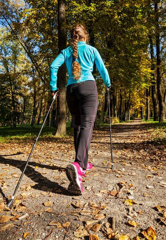 Nordic walking adventure and exercising concept - woman hiking withnordic walking poles in park, stock photo