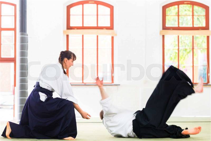 Man and woman fighting at Aikido training in martial arts school , stock photo