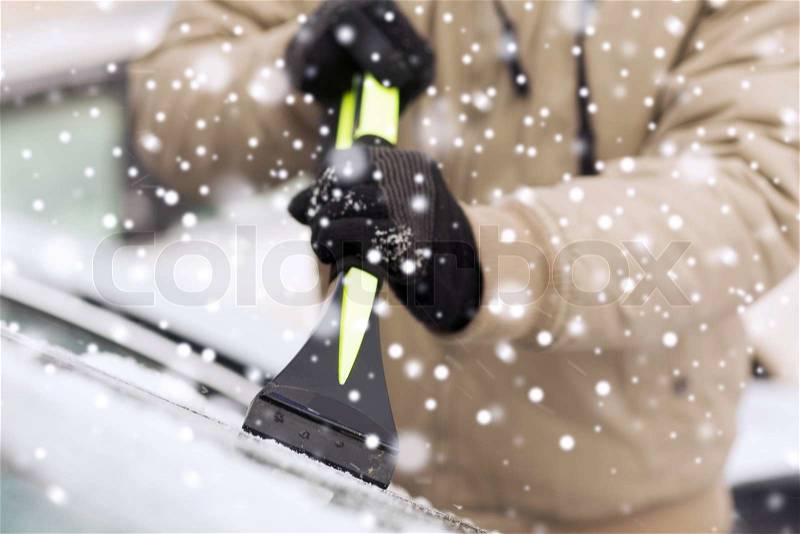 Transportation, winter, weather, people and vehicle concept - closeup of man cleaning snow from car windshield with brush, stock photo