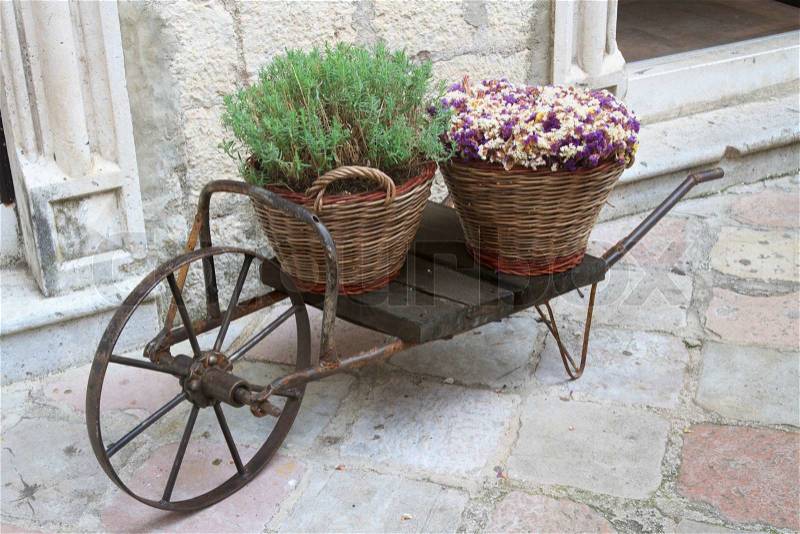 Decorative cart with baskets and flowers on the street close up , stock photo