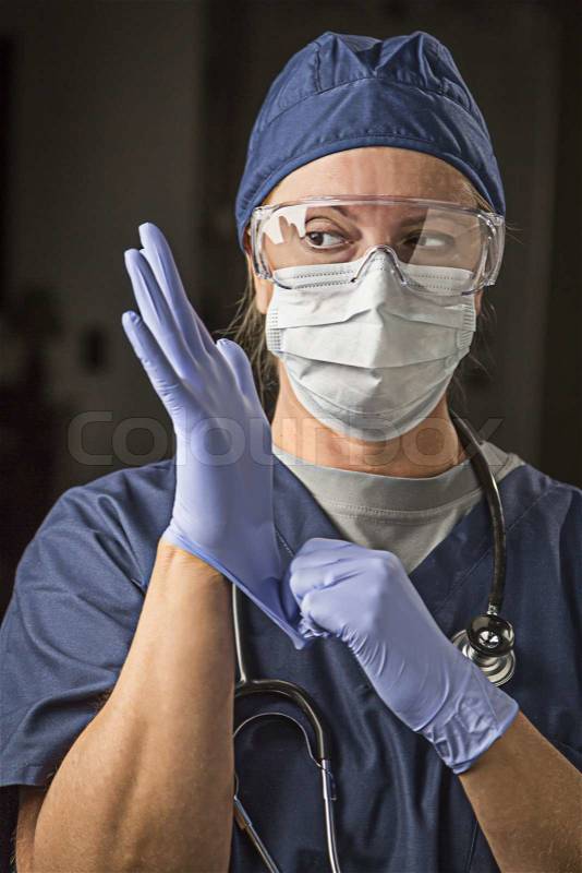 Concerned Female Doctor or Nurse Putting on Protective Facial Wear and Surgical Gloves, stock photo