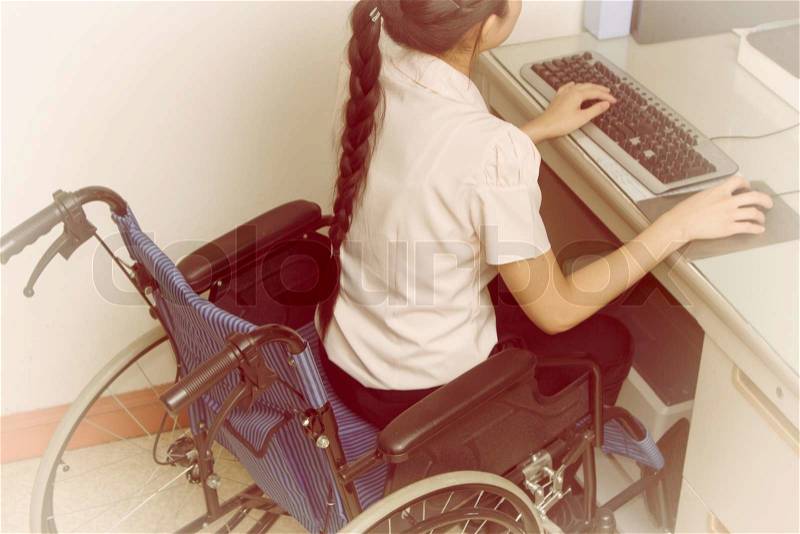 Asia woman in wheelchair working on computer in the office, stock photo