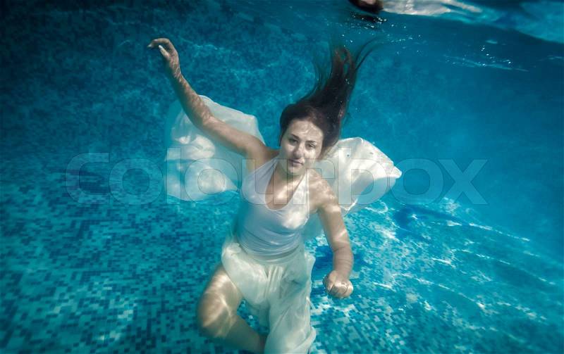 Beautiful woman with long hair swimming underwater at pool, stock photo