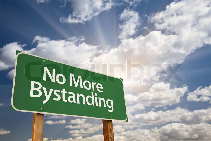 No More Bystanding Green Road Sign with Dramatic Clouds and Sky, stock photo