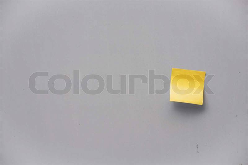 Yellow post-it note on a grey wall, stock photo