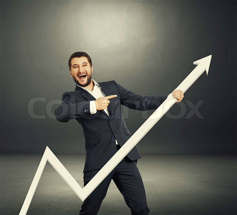 Excited businessman pointing at white pointer and laughing. photo in the dark room, stock photo