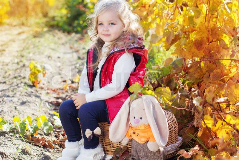 Adorable happy little girl with is wearing winter clothes with her rabbit toy on the nature, stock photo