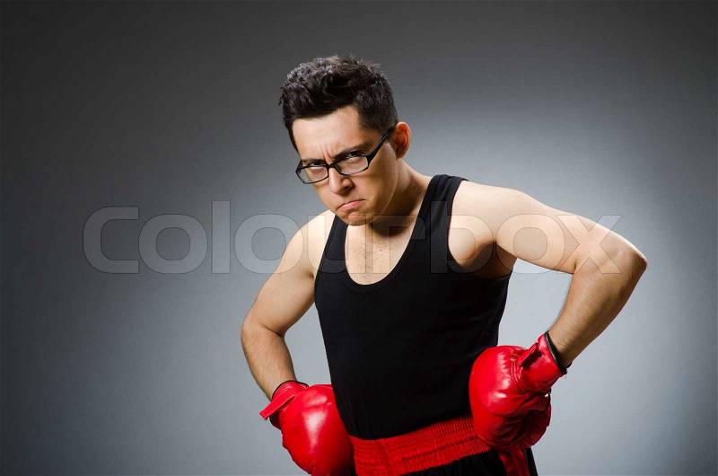 Funny boxer with red gloves against dark background, stock photo