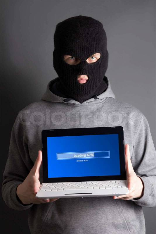 Masked hacker with loading computer over grey, stock photo