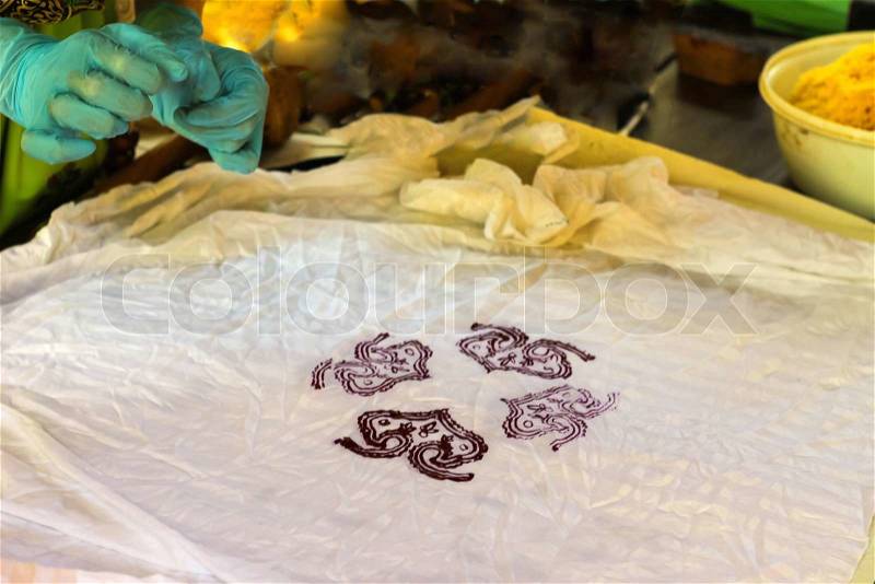 Artist prints stamped pattern on fabric, stock photo