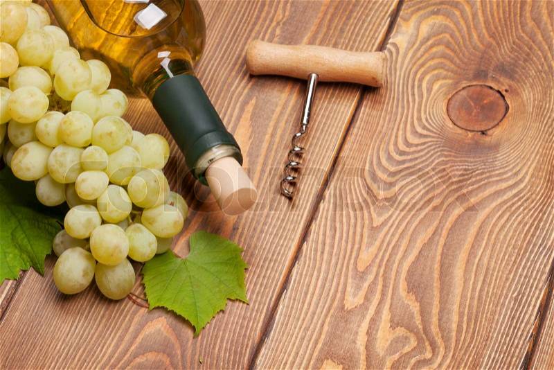 White wine bottle and bunch of white grapes on wooden table background with copy space, stock photo