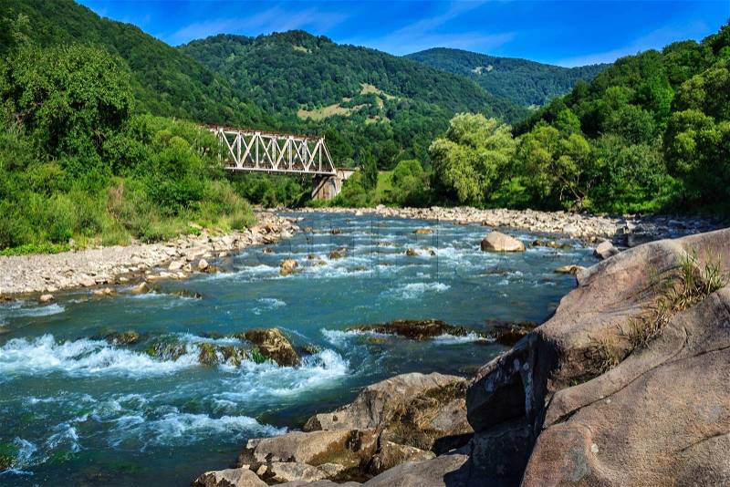 Iron Bridge and a giant stone on the opposite side of the river in the mountains, stock photo