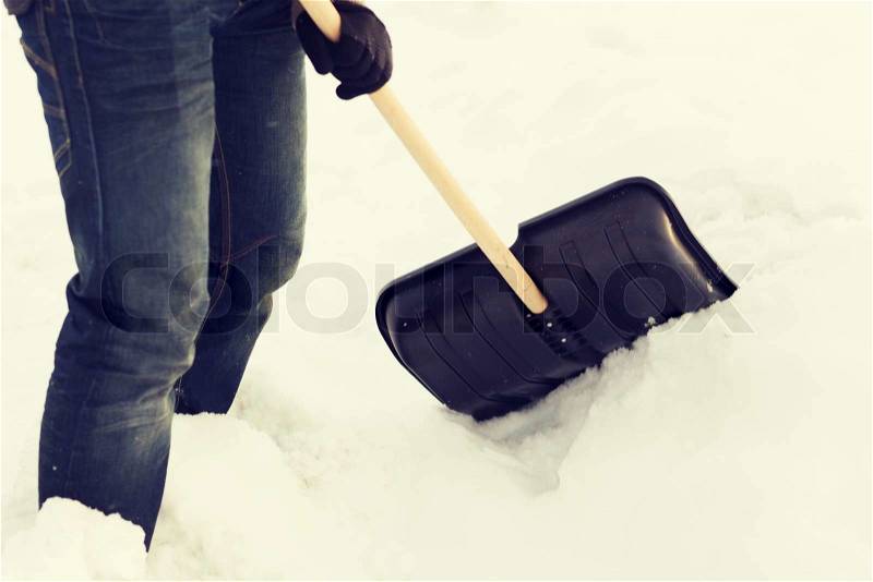 Winter and cleaning concept - closeup of man shoveling snow from driveway, stock photo